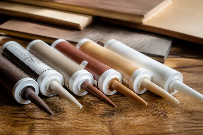 Choix du joint parquet bois : tubes de mastic acrylique et polyuréthane présentés.