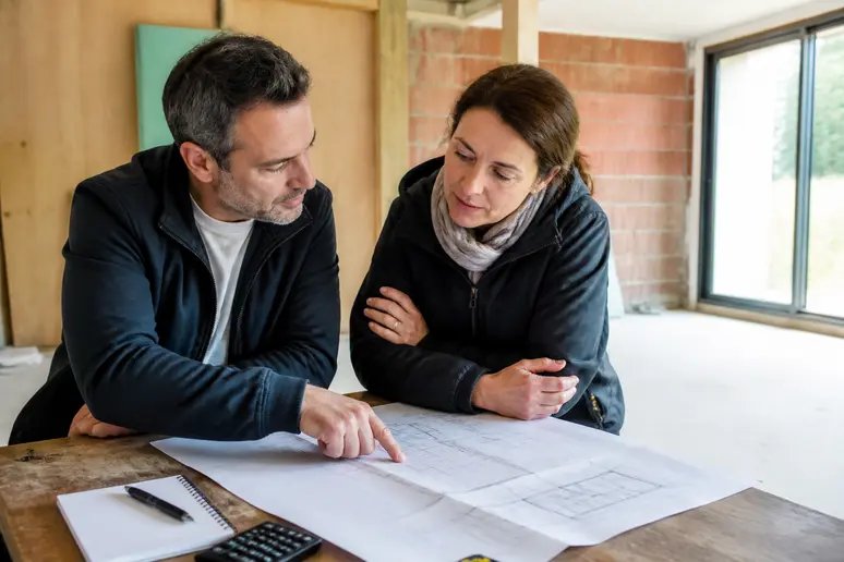 Couple examinant les plans d'une maison bois plain pied pour leur projet de construction.
