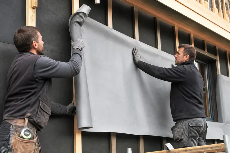Pose professionnelle d'un pare pluie ossature bois sur une structure de maison.