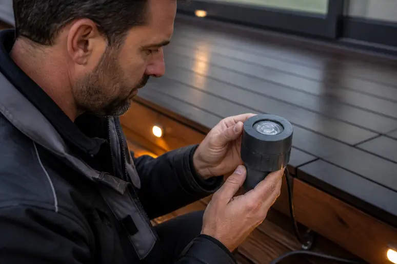 Expert vérifiant l'indice IP d'un spot terrasse bois pour une installation extérieure étanche.
