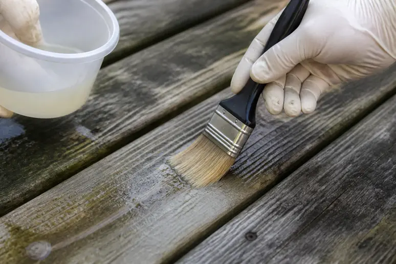 Application d'un traitement de dégrisement sur les taches noires d'une terrasse en bois
