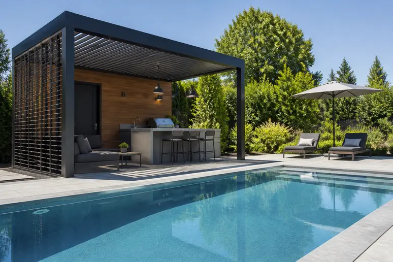 Pool house en aluminium moderne installé sur une terrasse au bord d'une piscine