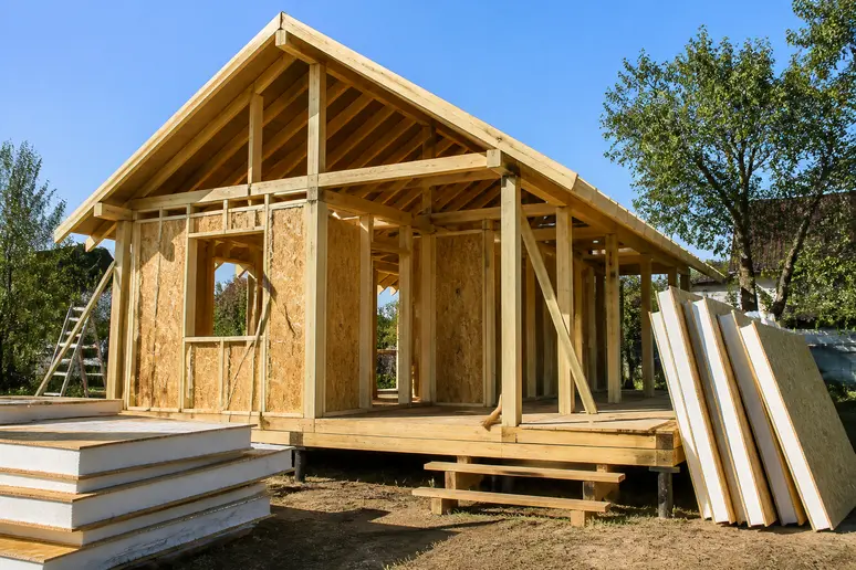 Chantier d'une petite maison en bois montrant l'ossature et les panneaux isolants