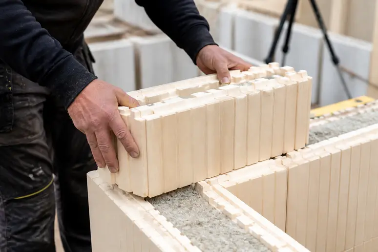 Assemblage des blocs isolants d'une maison en kit autoconstruction par un particulier sur le chantier
