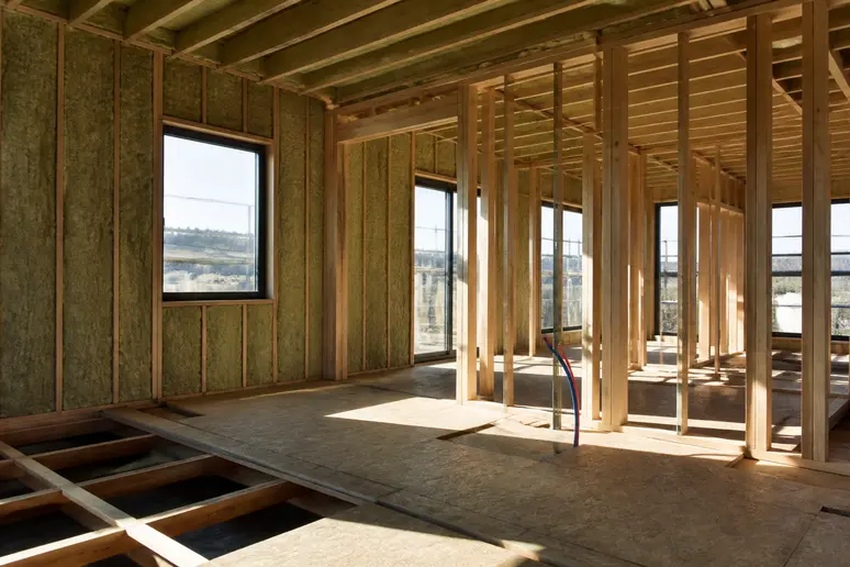 Chantier d'une maison neuve montrant l'ossature bois et l'isolation intérieure avant les finitions