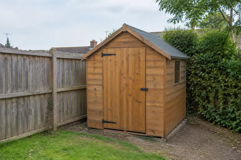 Abri de jardin en bois installé dans un espace extérieur près d'une clôture