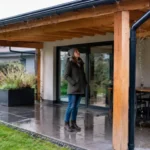 Propriétaire profitant d'un abri terrasse en bois adossable étanche par temps de pluie