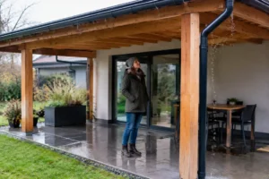 Propriétaire profitant d'un abri terrasse en bois adossable étanche par temps de pluie
