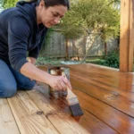 Personne appliquant de l'huile sur des lames de sol pour un bon Entretien terrasse bois au quotidien