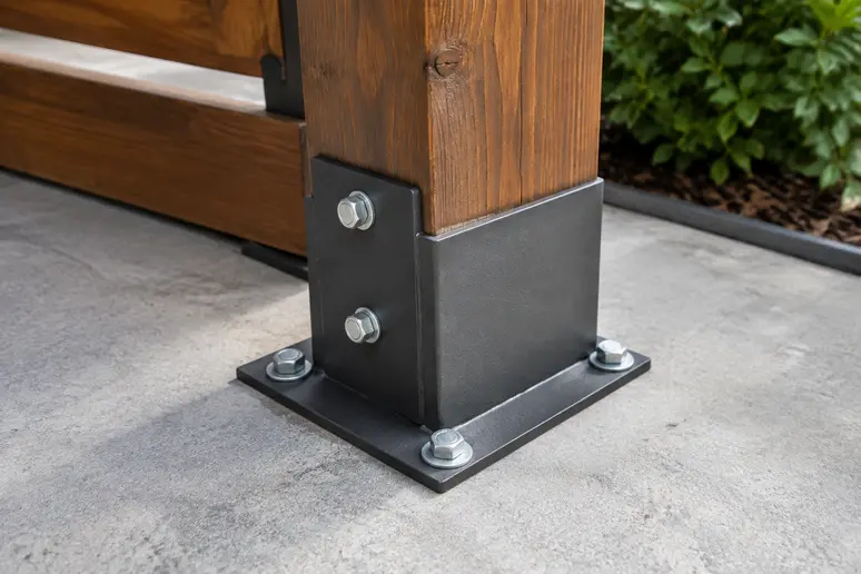 Pied de poteau et platine de fixation métallique ancrés sur la dalle d'une terrasse en bois.