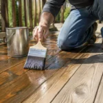 Application d'une protection sur une terrasse en bois finition naturelle avec un pinceau plat
