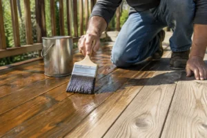 Application d'une protection sur une terrasse en bois finition naturelle avec un pinceau plat