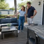 Propriétaires installés sur leur nouvelle terrasse en bois pour mobil home dans un camping ensoleillé.