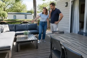 Propriétaires installés sur leur nouvelle terrasse en bois pour mobil home dans un camping ensoleillé.