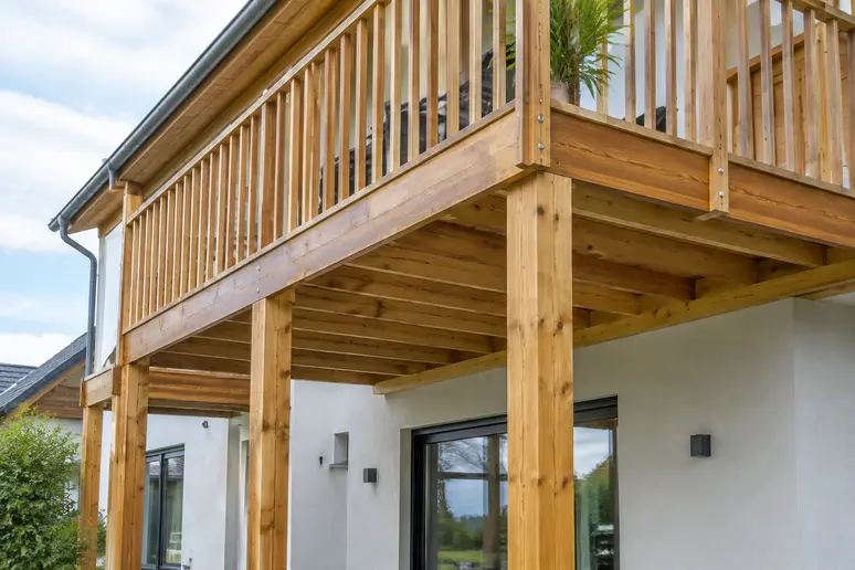 Structure de terrasse suspendue en bois avec ses appuis et poutres porteuses le long du bâtiment.