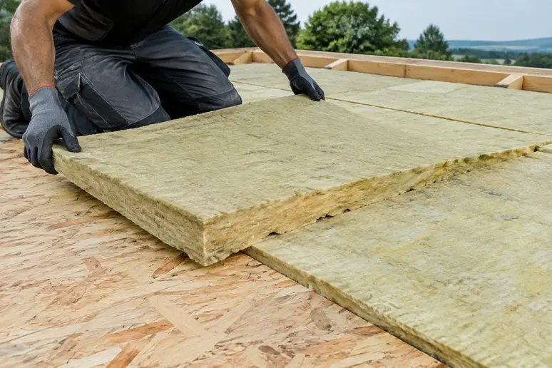 Pose d'une isolation thermique au-dessus de panneaux OSB sur un toit terrasse bois.